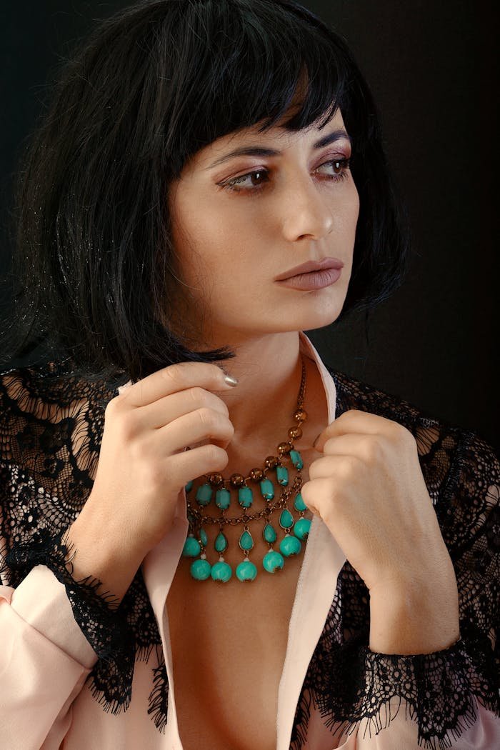 Portrait of a stylish woman wearing a turquoise necklace and lace apparel.